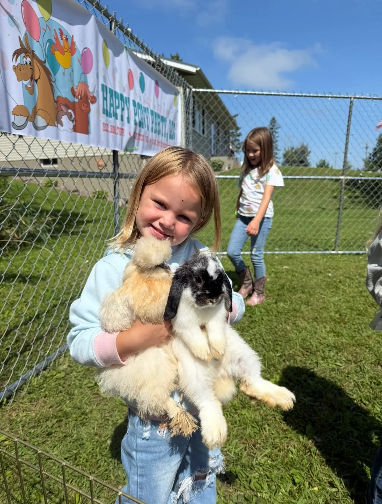 A girl holding a silkie chicken and a lop-eared rabbit at a Pony Parties Express event